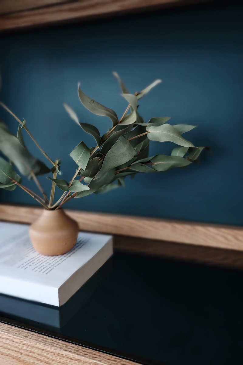 comedor de madera con base de herrería, sillas de terciopelo azul y consola de madera con herrería, cortinas y muro color azul